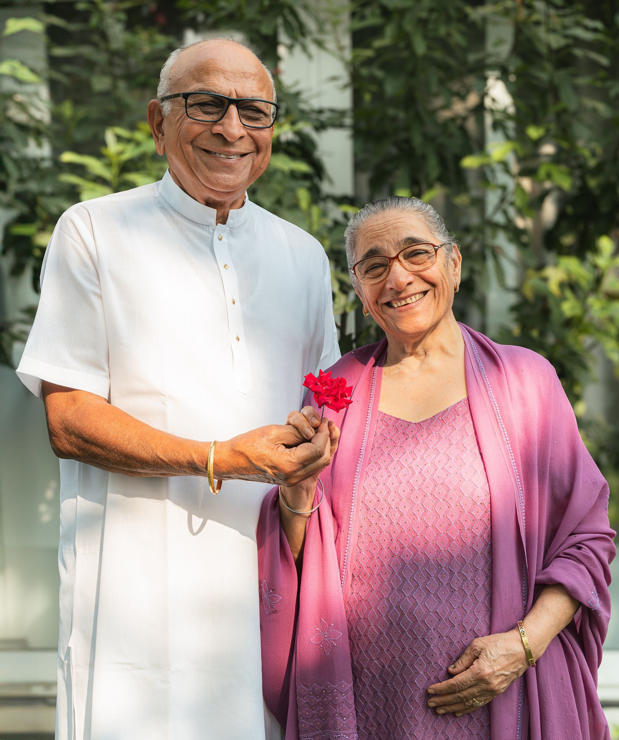 A smiling retired Indian couple in a garden