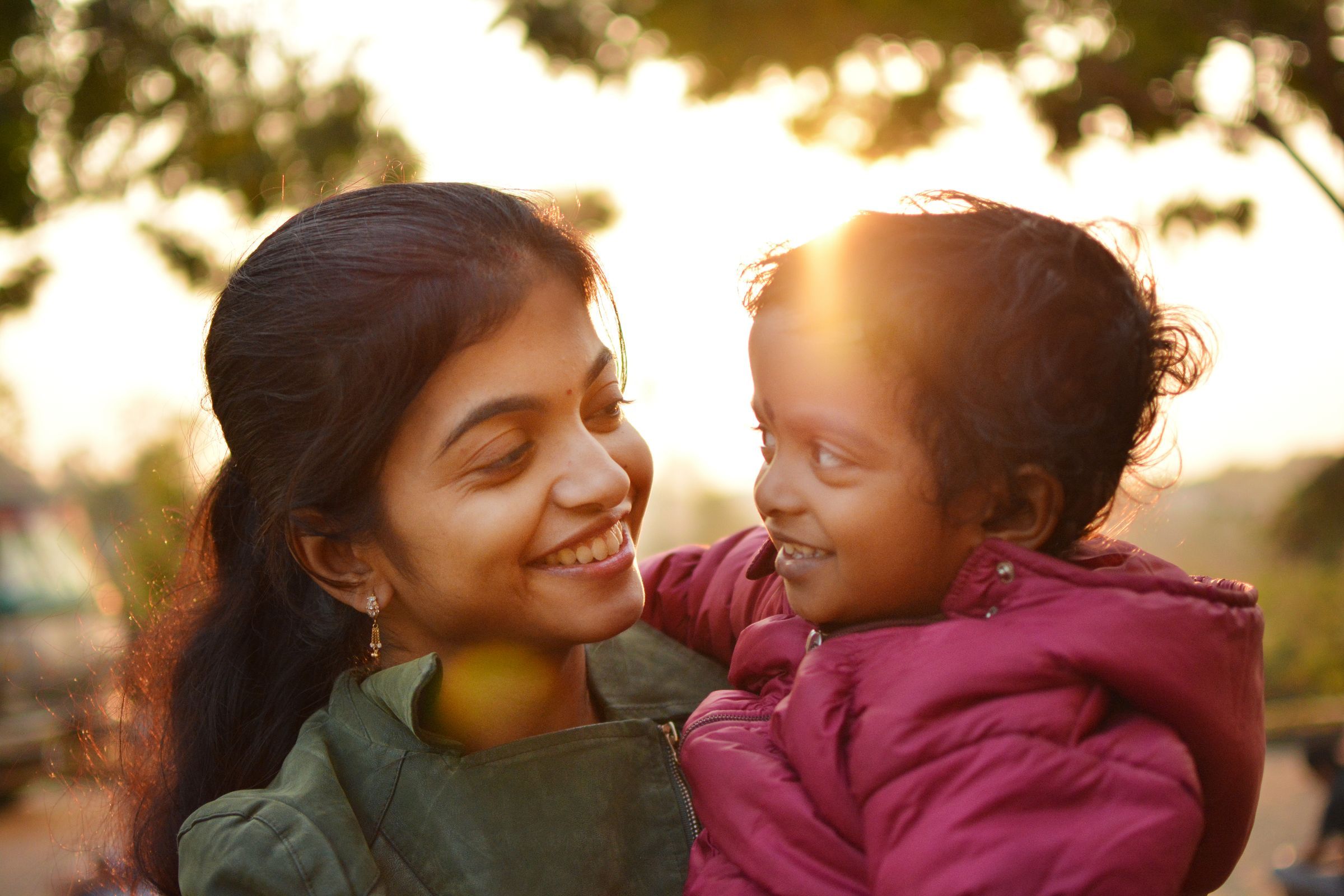 A young mother smiling at her daughter in golden evening light