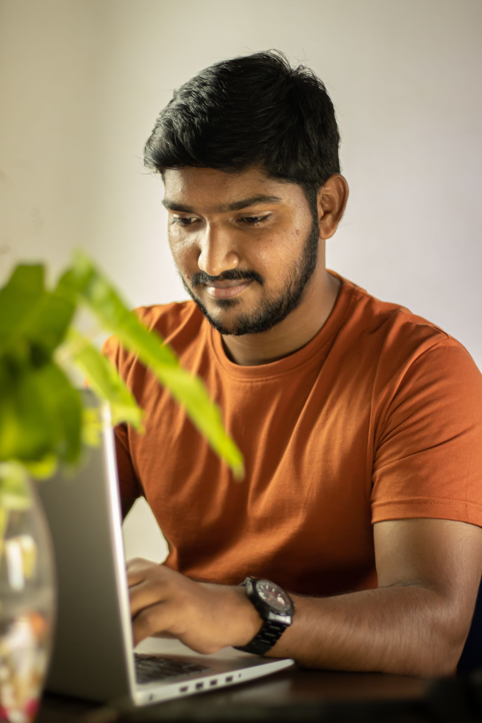 A young investor concentrating on his laptop in soft window light