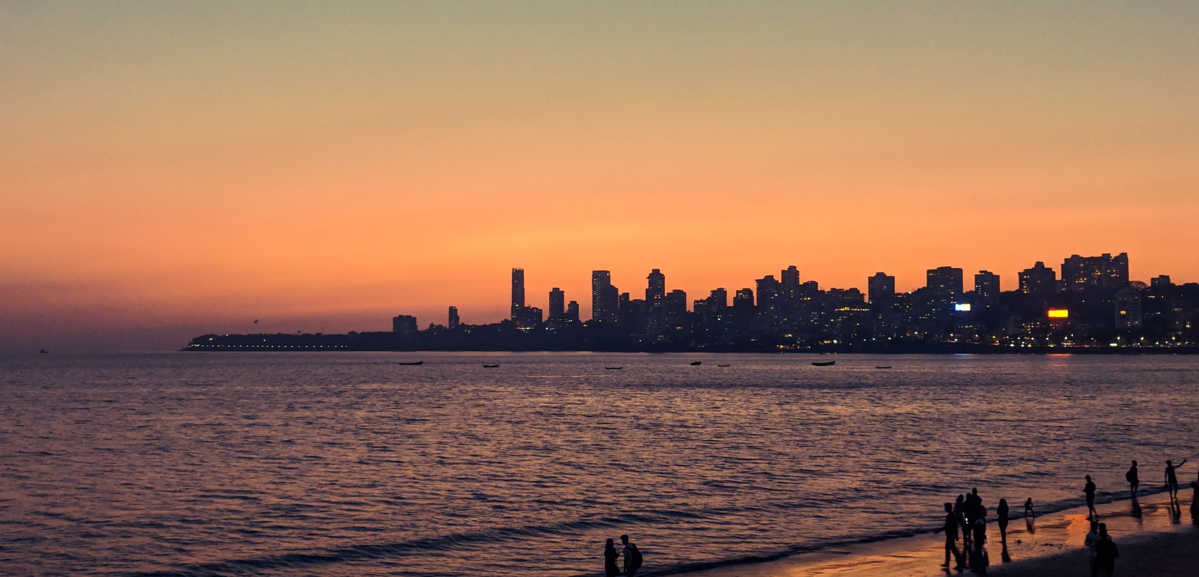 The Mumbai skyline silhouetted against an orange dusk sky